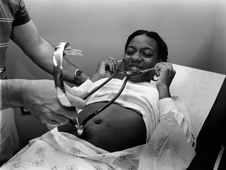 Een zwangere moeder luistert met de stethoscoop van de dokter naar de hartslag van haar baby. Beeld Mel Rosenthal