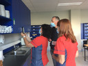 Twee leden van het poetsteam testen de QR-code die Peter Boey (achteraan) net in de keuken van het gebouw C op campus Schoonmeersen aangebracht heeft.