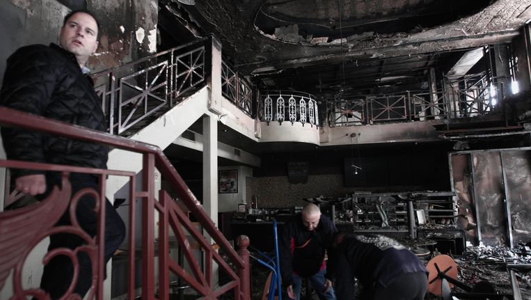 Schoonmakers aan het werk in een uitgebrand café in het centrum van Athene. Beeld AP