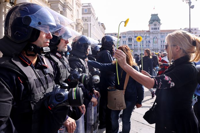 Demonstranten tonen bloemen aan de Italiaanse politie tijdens een protest in de haven van Trieste tegen de Green Pass.