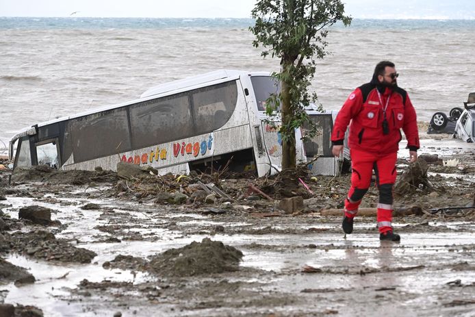 Un autobus è stato spazzato via sulla spiaggia da questa frana di fango.  Ci sono macchine nel mare davanti.