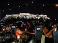 Bezoekers van een bar in Athene, met op de achtergrond de Akropolis.
