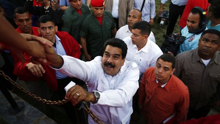 De Venezolaanse president Maduro (midden) komt werknemers in een Venezolaanse fabriek dinsdag een hart onder de riem steken. Beeld reuters
