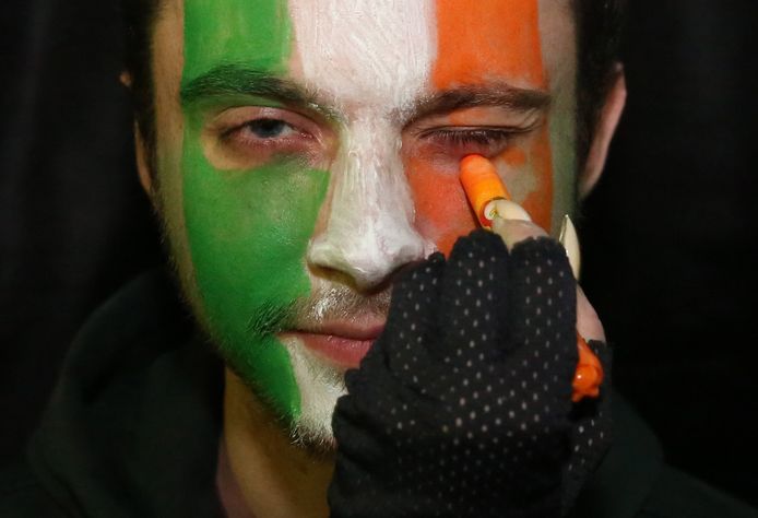 Een man verft zijn gezicht in de Ierse nationale driekleur.