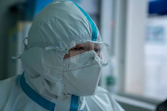 Een Chinese dokter in beschermingskledij terwijl hij een patiënt, die besmet is met het coronavirus, onderzoekt. 