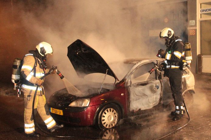 Brandweerlieden blussen op oudejaarsavond een autobrand in de Utrechtse wijk Overvecht.