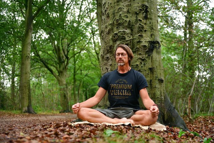 Sven Honing is ademcoach mediteert in het bos bij een boom. ,,In de natuur ervaar ik rust en ruimte."