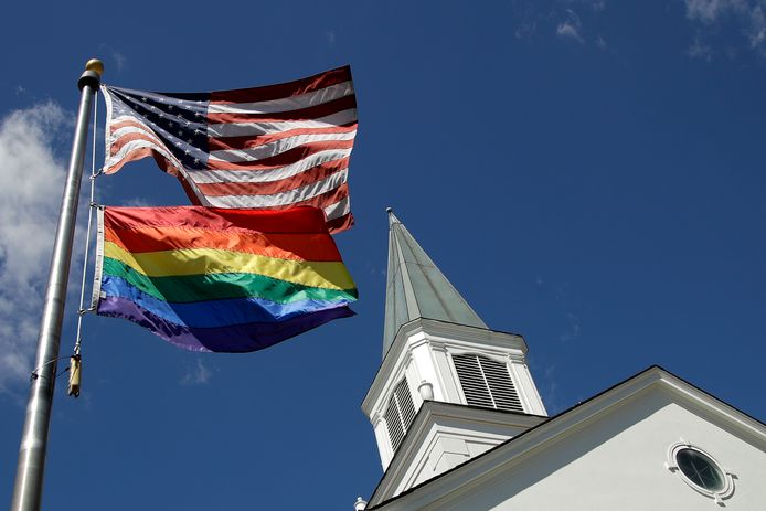 Een Amerikaanse vlag en een regenboogvlag voor een kerkje in de VS. De Trump-regering wilde zorgaanbieders toestaan om zorgverlening aan lhbt'ers te weigeren om religieuze redenen, maar daar heeft de rechter een stokje voor gestoken.