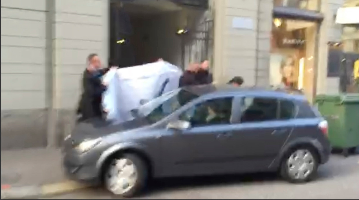 Foto van het moment waarop via de zij-ingang van het hotel in Zürich één van de FIFA-officials wordt weggeleid door de politie. Beeld ap