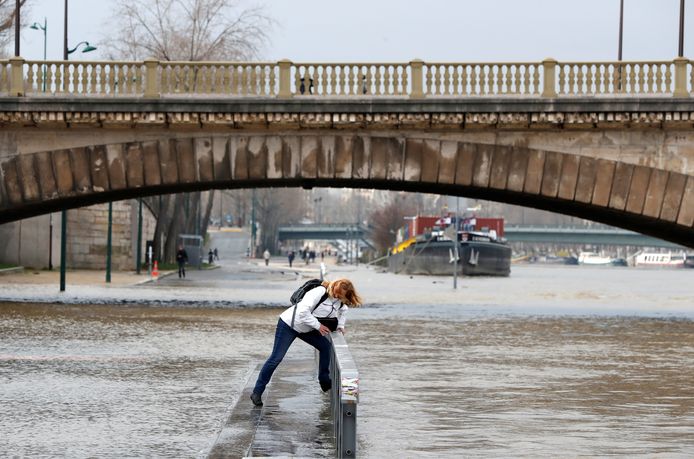 Haren in de wind, voeten in het nat. Deze vrouw trotseert het slechte weer in Parijs, waar de Seine stilaan buiten haar oevers treedt.