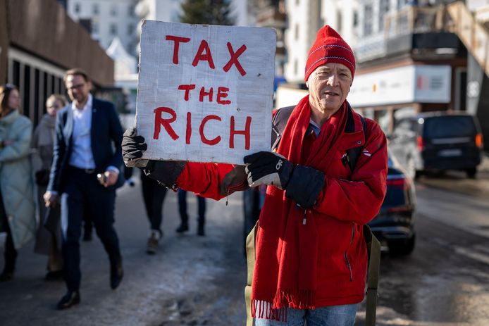 Archiefbeeld. De Britse miljonair Phil White houdt een pancarte vast met de boodschap "Belast de rijken", tijdens de bijeenkomst van politieke en economische leiders in Davos, Zwitserland. (18/01/23)