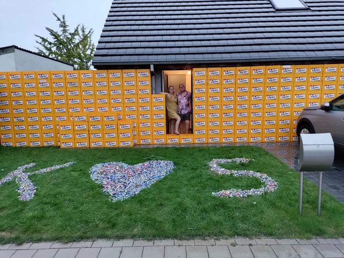 Sofie en Kevin bij de muur van bierbakken die hun vrienden voor hun huis hebben gebouwd.