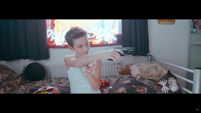 ►Een kind speelt met een vuurwapen. Een beeld uit de eveneens felbesproken clip van het gecontesteerde nummer 'Kind van de Duivel'. Beeld rv