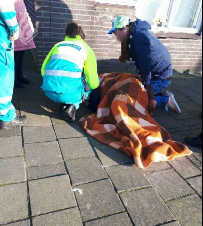De gestruikelde man wordt - op het ongelijkliggende trottoir - verzorgd door het ambulancepersoneel.