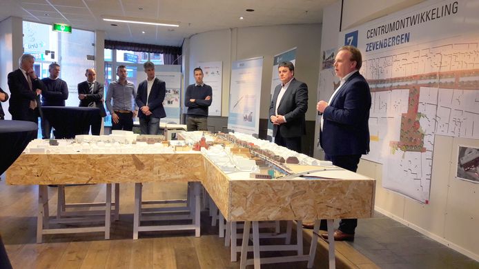 De wethouders Kamp en Zwiers (re) spreken het publiek toe. Links luisteren de aannemers mee.