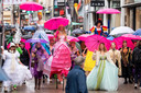 Plezier in de regen onder de roze of paarse paraplu in de Ketelstraat in Arnhem tijdens het laatste weekend van het Sprookjesfestival.