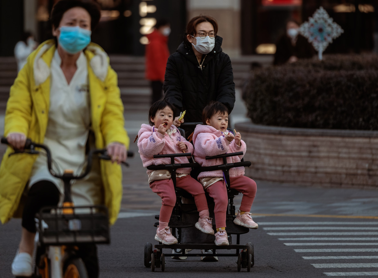 Een vrouw in Shanghai duwt een kinderwagen met daarin een tweeling. Beeld ANP / EPA