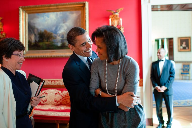  President Barack Obama omhelst first lady Michelle Obama in de Red Room van het Witte Huis,
met senior adviseur Valerie Jarrett, 20 maart 2009. Beeld Pete Souza / The White House