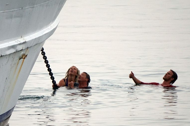 Activisten zijn in het water gesprongen en proberen de boot tegen te houden die de migranten naar Turkije terug zal brengen. Beeld afp