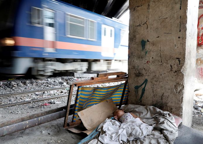 In het Filipijnse Manilla slaapt een baby in een provisorisch bedje naast de spoorrails. Foto Dondi Tawatao
