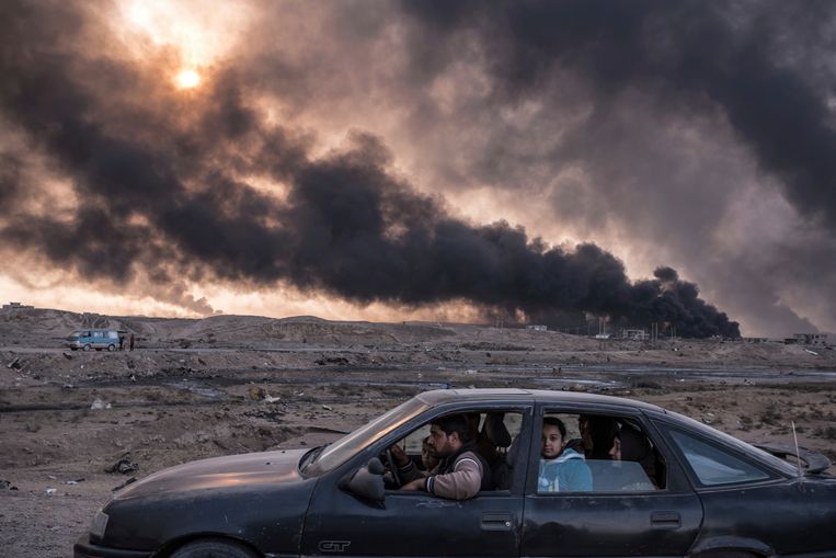 Irak, 2016. Een familie ontvlucht de gevechten in Mosul, terwijl in Qayyara oliebronnen branden die zijn aangestoken door IS.  Beeld AP