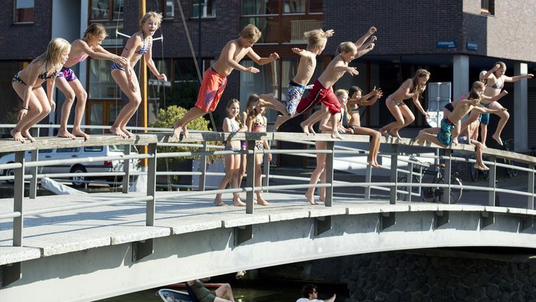 Kinderen springen van een brug aan de Stokerkade in Amsterdam afgelopen vrijdag, op de eerste tropische septemberdag sinds 1949. Beeld anp