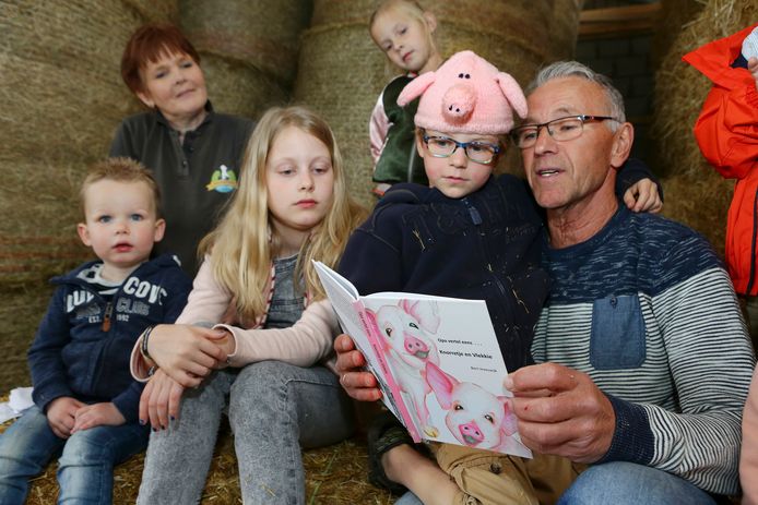 Bert Vreeswijk leest voor aan kinderen tijdens de presentatie van zijn boekje op de kaasboerderij van familie Van Beest in Spijk.
