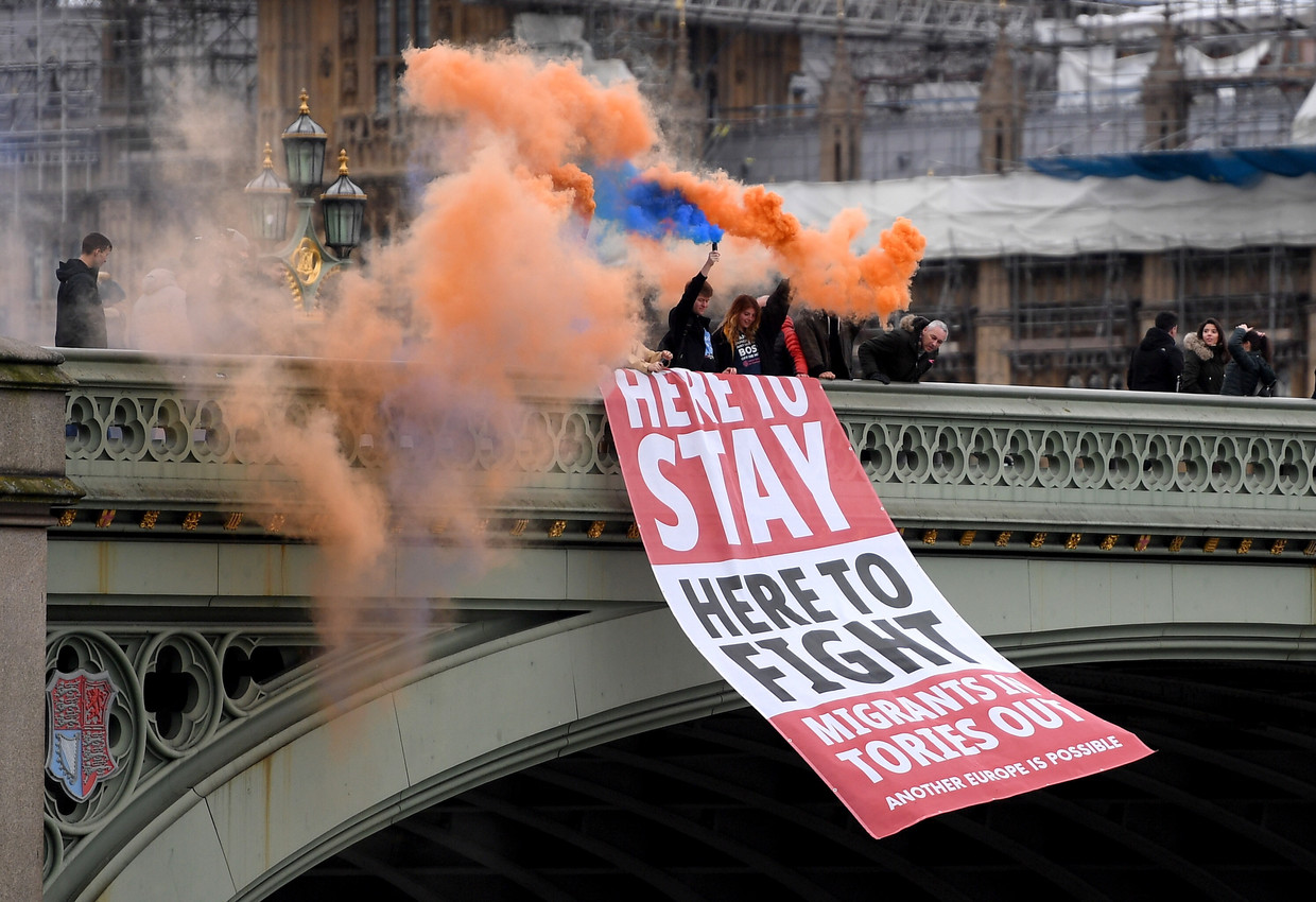 Strijdlustig tot het einde: anti-Brexit-betogers rollen luttele uren voor het Britse vertrek uit de EU bij het parlementsgebouw in Londen een banier uit met onderaan de leus ‘Migranten erin, Tory’s eruit’.  Beeld Foto Andy Rain / EPA