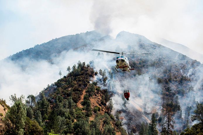 Een helikopter haalt water om bosbrand Ferguson te blussen.