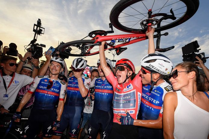 Remco Evenepoel in de rode trui viert de eindzege met zijn ploeggenoten.
