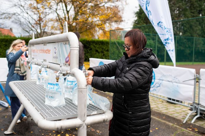 Een vrouw tapt water van de noodinstallatie. Elke inwoner heeft bij problemen met het drinkwater recht op 3 liter per dag, een huisdier heeft recht op 1 liter.