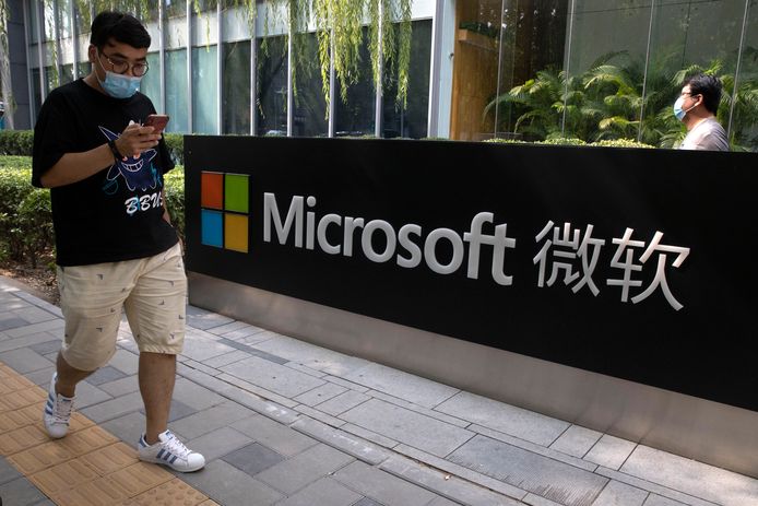 Een man kijkt op zijn telefoon terwijl hij een Microsoft-kantoor in Beijing voorbij wandelt.