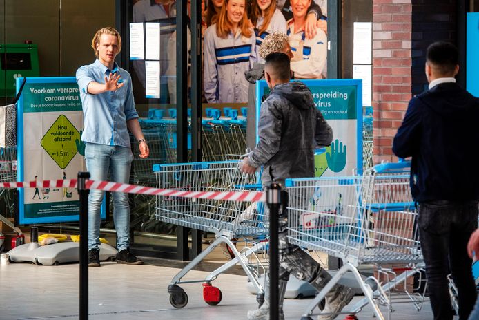 Een supermarktmedewerker regelt het verkeer bij de ingang van de Albert Heijn-vestiging in het Arnhemse winkelcentrum Presikhaaf.
