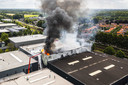 Dronefoto van de brand die vorige week maandag de opslaghal van aanmaakblokjesfabriek Fire-Up in Oisterwijk in de as legde.  Omliggende bedrijven bleven ternauwernood gespaard.