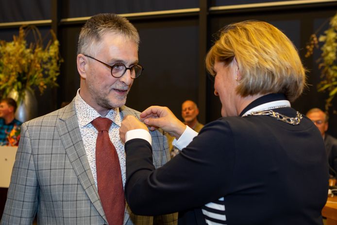 Raadslid Henk Geluk krijgt het lintje opgespeld door burgemeester Sijbers van Tholen.