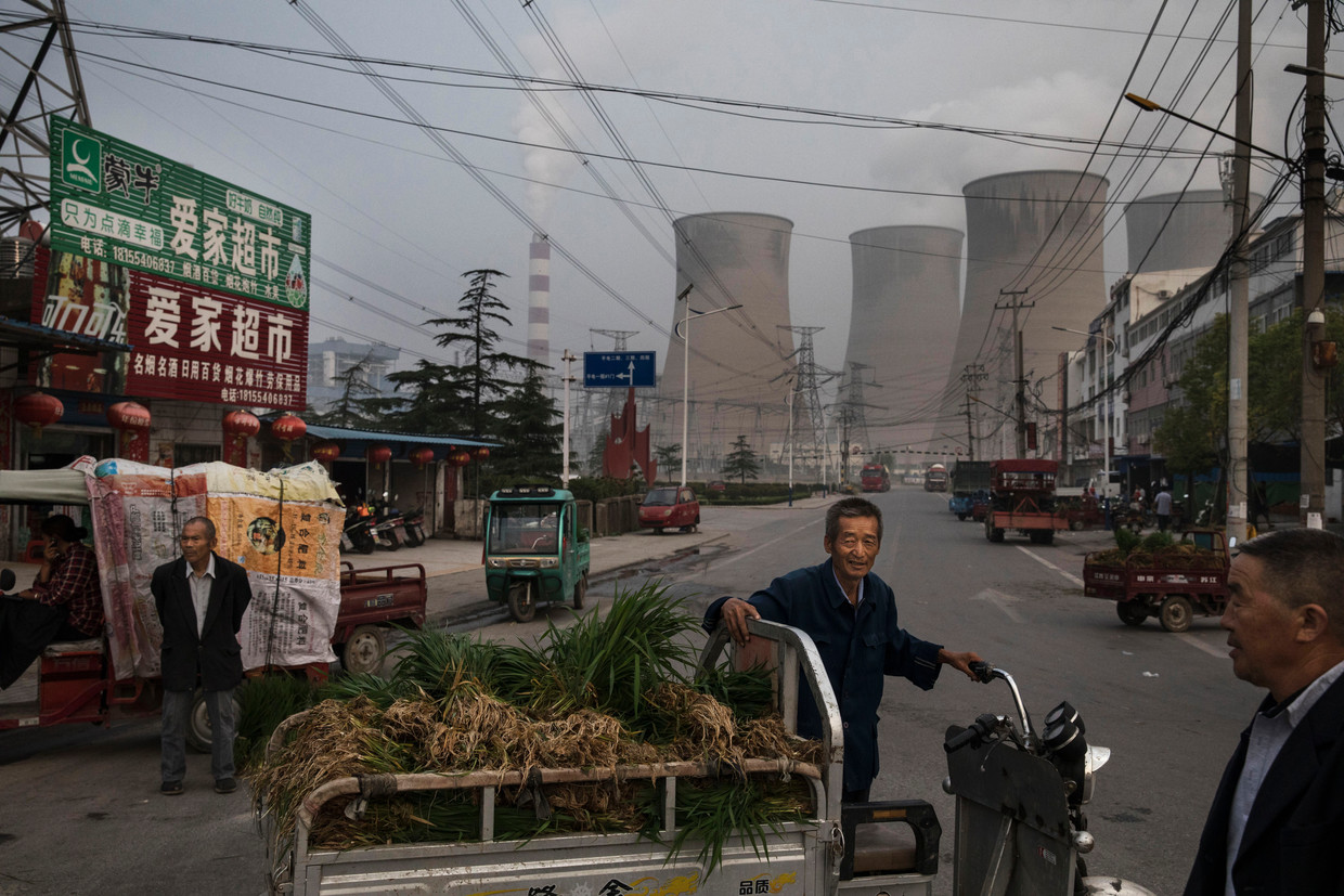 Chinese kooplieden op staat in Huainan in de oostelijke provincie Anhui. Op de achtergrond staat een grote kolencentrale. Beeld Getty Images
