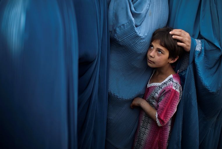 Een Afghaans meisje staat met haar moeder in de rij voor een voedselpakket in Kabul, 2010. Het Westen was van plan de positie van vrouwen te verbeteren en meisjes naar school te krijgen. In 2021 gaan er ruim 8 miljoen kinderen meer naar school dan in 2001. Beeld Reuters