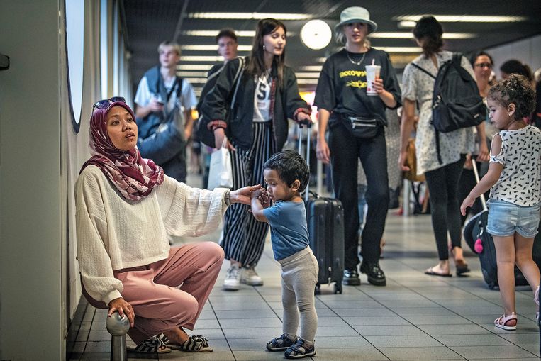Een moeder speelt geduldig met haar zoontje terwijl de rest van de familie in de rij staat op Schiphol.
 Beeld  Guus Dubbelman / de Volkskrant