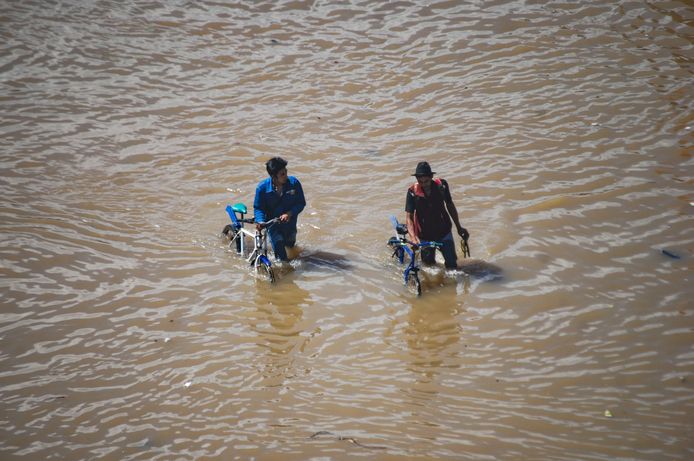 Indonesische fietsers duwen hun tweewieler door het hoge water in Bandung, nadat de straten door het regenseizoen zijn overstroomd. Foto Timur Matahari