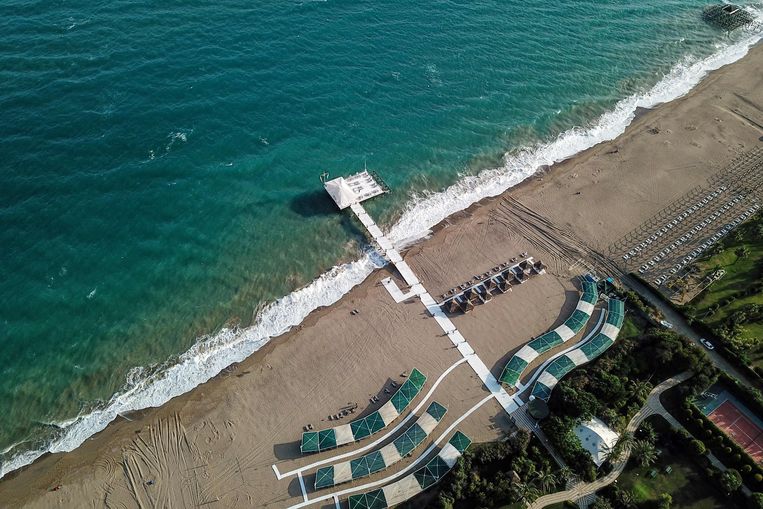 Eind juni, een strand in Antalya. Normaal moet je er 's ochtends heel vroeg bij zijn om een plekje te bemachtigen. Nu ligt het toerisme zo goed als stil. Beeld AFP