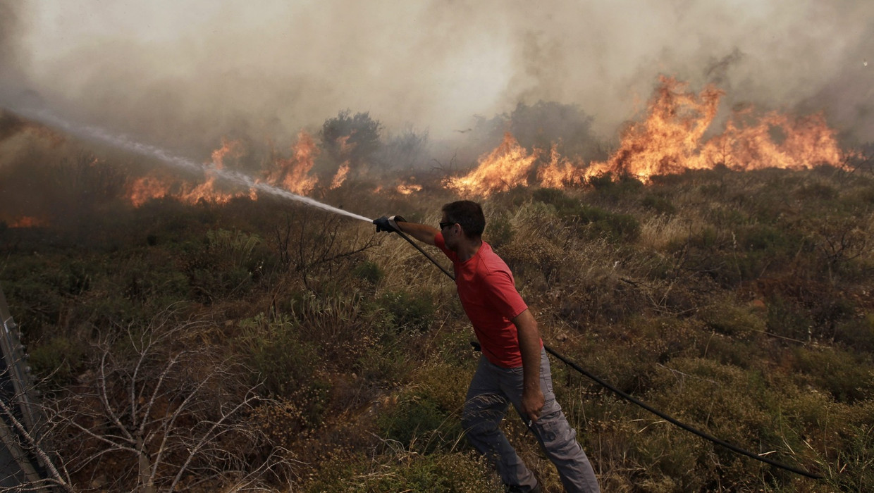 Een vrijwilliger probeert een bosbrand te blussen in de buurt van Athene. Beeld EPA