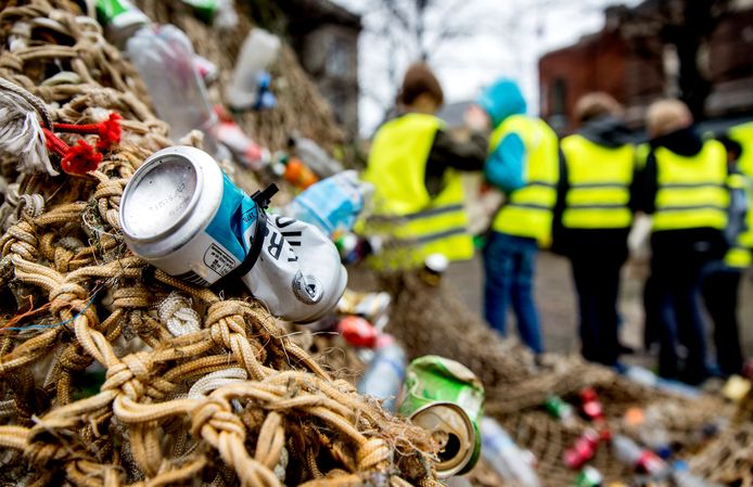 Actievoerders bij een standbeeld van Neptunus op het Plein bij de Tweede Kamer. De milieuorganisatie wil met de actie politici oproepen om statiegeld op kleine flesjes en blikjes in te voeren.