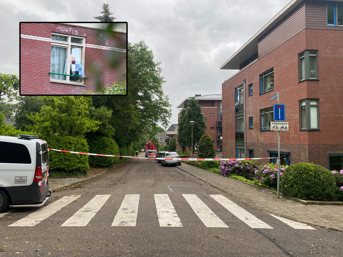 De politie heeft een deel van de Händelstraat in Groesbeek afgezet. Inzet: de man zit in het kozijn en dreigt naar beneden te springen.