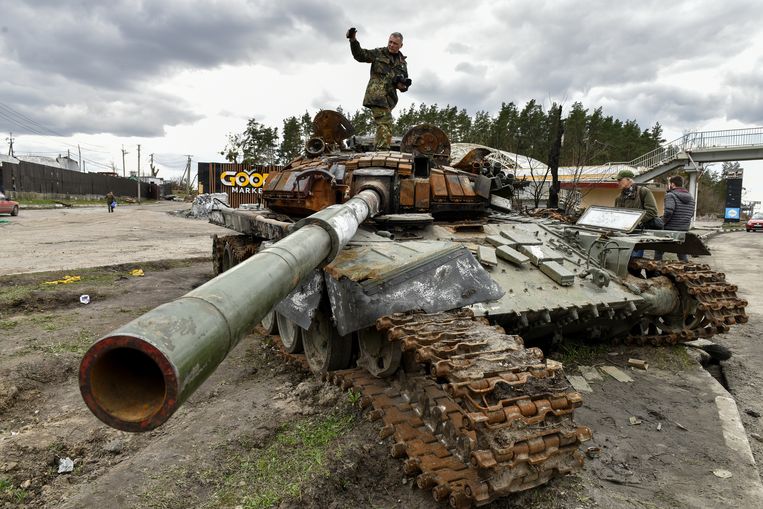 Een man staat op een vernietigde Russische tank in de buurt van de Oekraïense hoofdstad Kiev. Beeld ANP / EPA