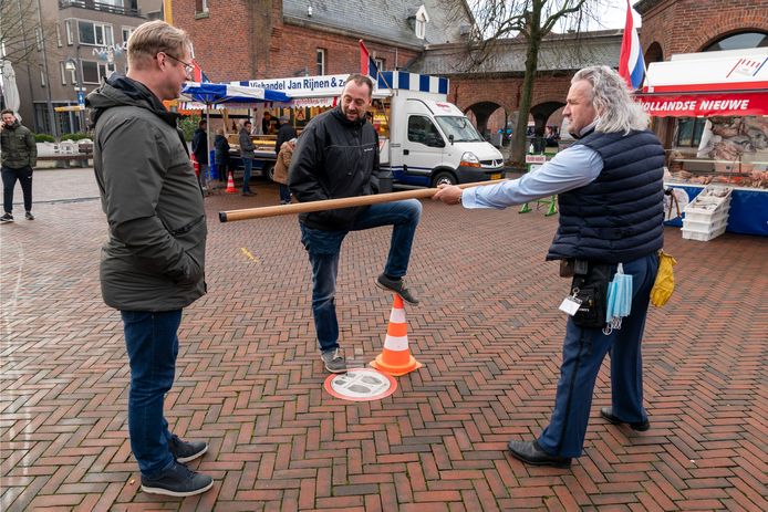 Straatartiest Jack Houben (rechts) houdt op de weekmarkt  in Waalwijk goed in de gaten of iedereen voldoende afstand houdt.