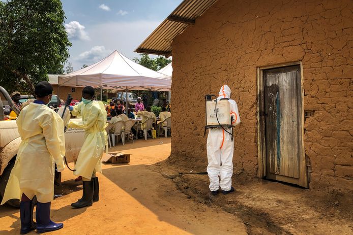 Een medewerker van de Wereld Gezondheidsorganisatie desinfecteert de deurpost van een huis waar twee ebola-gevallen werden geconstateerd.