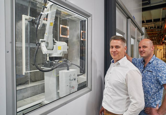 De nieuwe spuitrobot behandelt een kozijn. Daarnaast Ferry Peters en rechts Patrick Habraken.