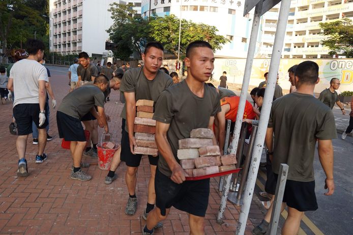 Soldaten van het Volksbevrijdingsleger helpen omwonenden van de Hong Kong Baptist University met het weghalen van stenen en wegversperringen.