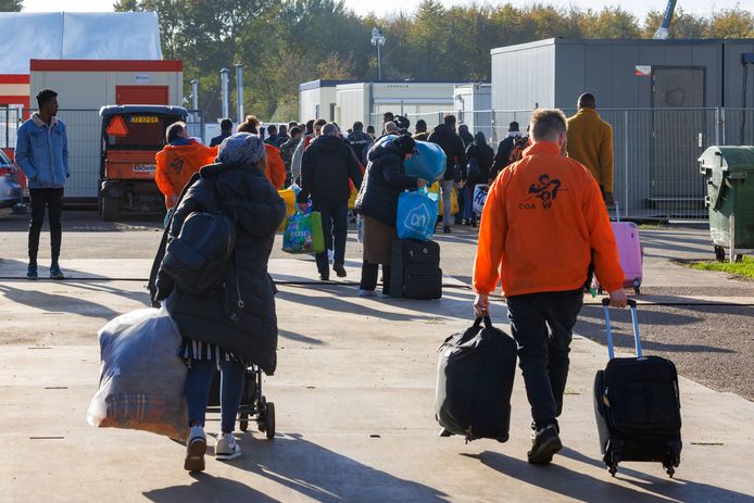 Een groep vluchtelingen loopt het terrein van de noodopvang in Biddinghuizen op.