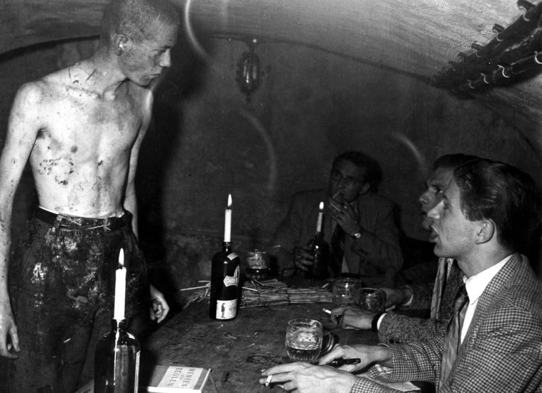 Ontgroening van een feut waarbij bierdrinkende ouderejaars hem in een kelder van achter een door kaarsen verlichte tafel toeschreeuwen, Nederland, 1962. Beeld Hollandse Hoogte / Spaarnestad Photo